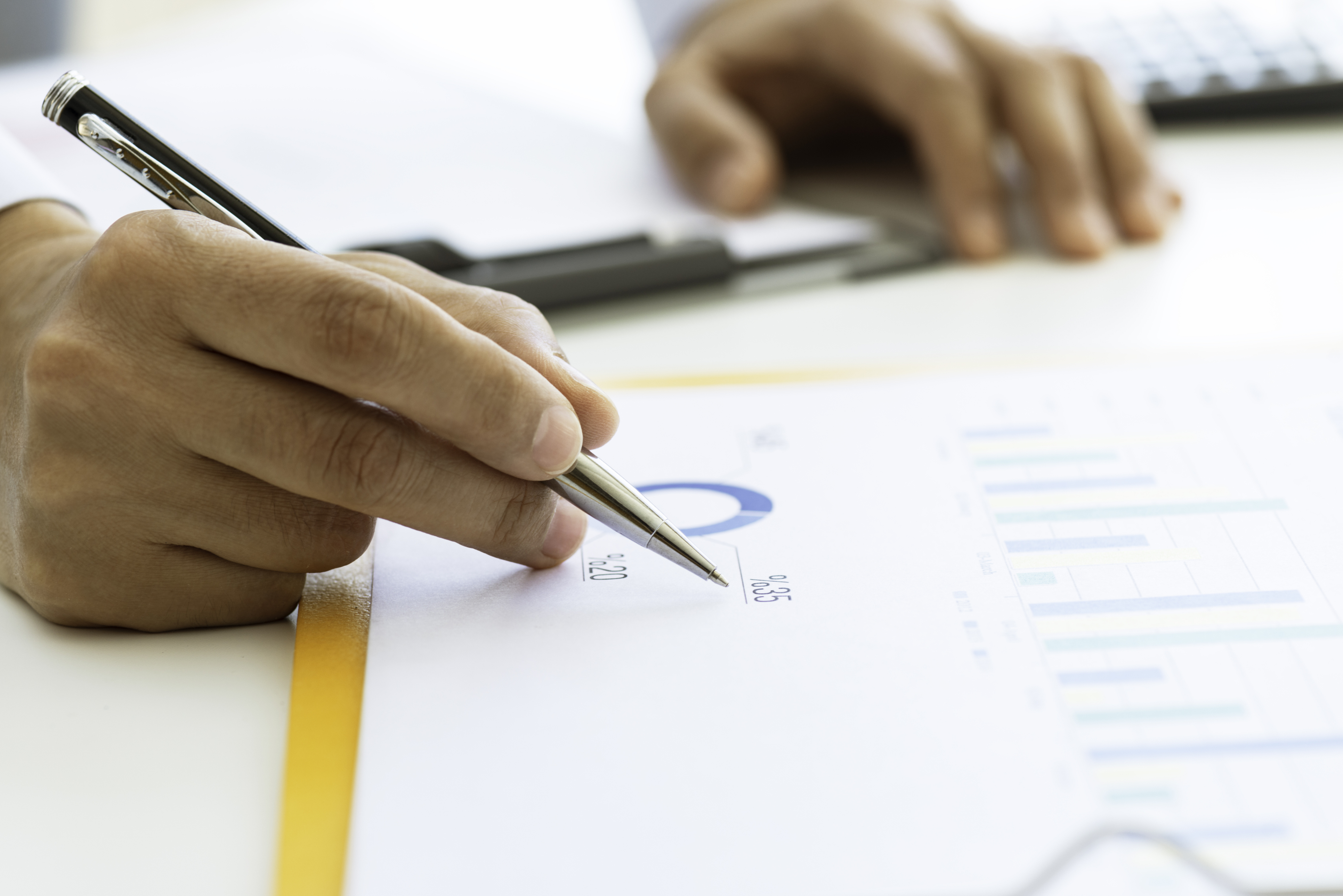 A person points a pen at a figure in a cashflow report.
