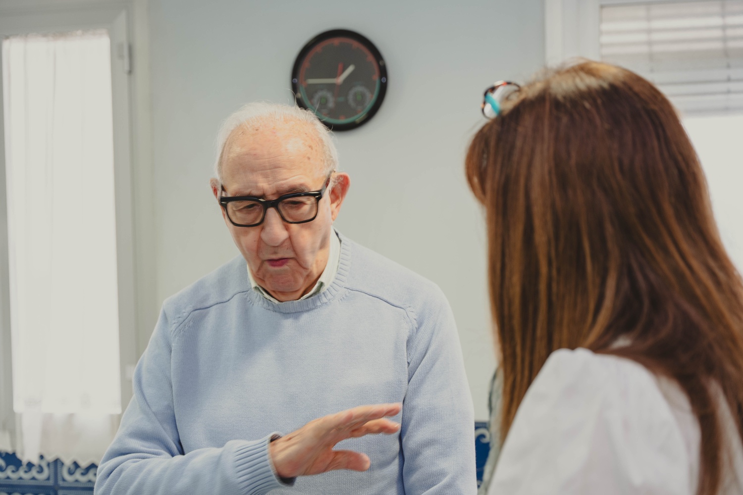 Elderly man talking with his adult daughter, showing family support and care indoors