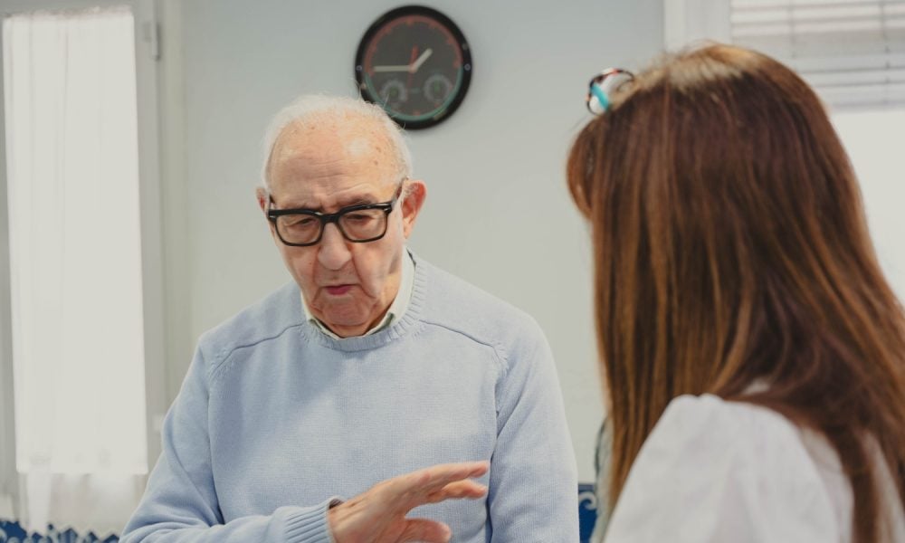 Elderly man talking with his adult daughter, showing family support and care indoors